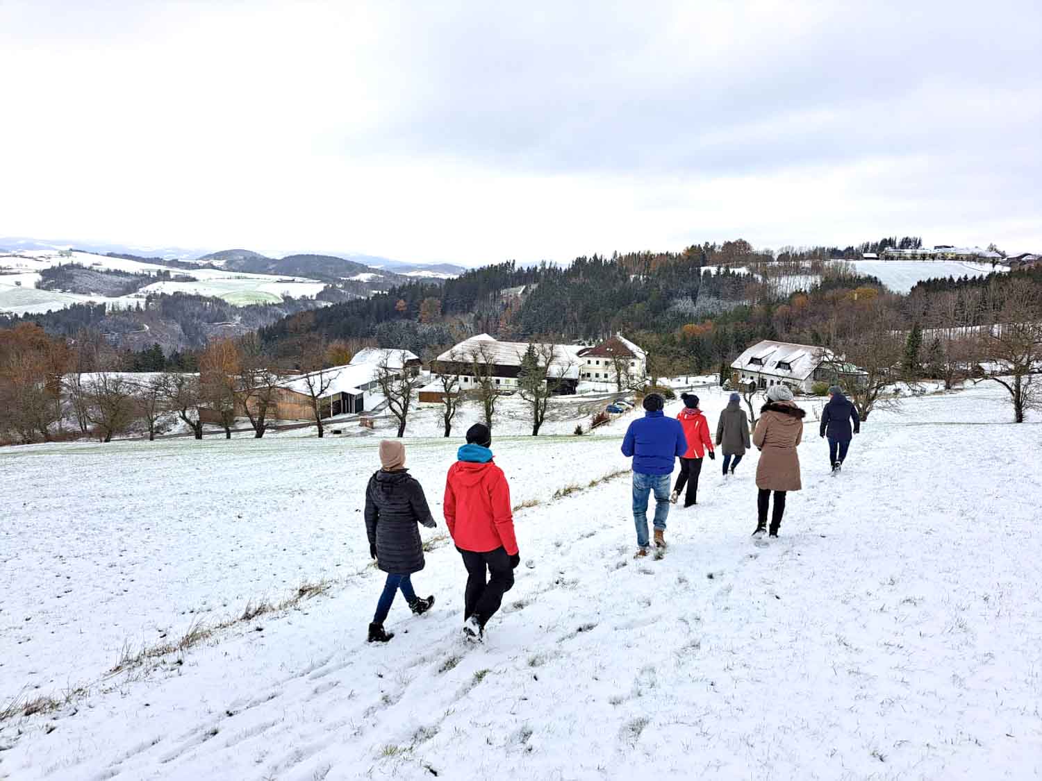 Menschen wandern durch verschneite Landschaft.