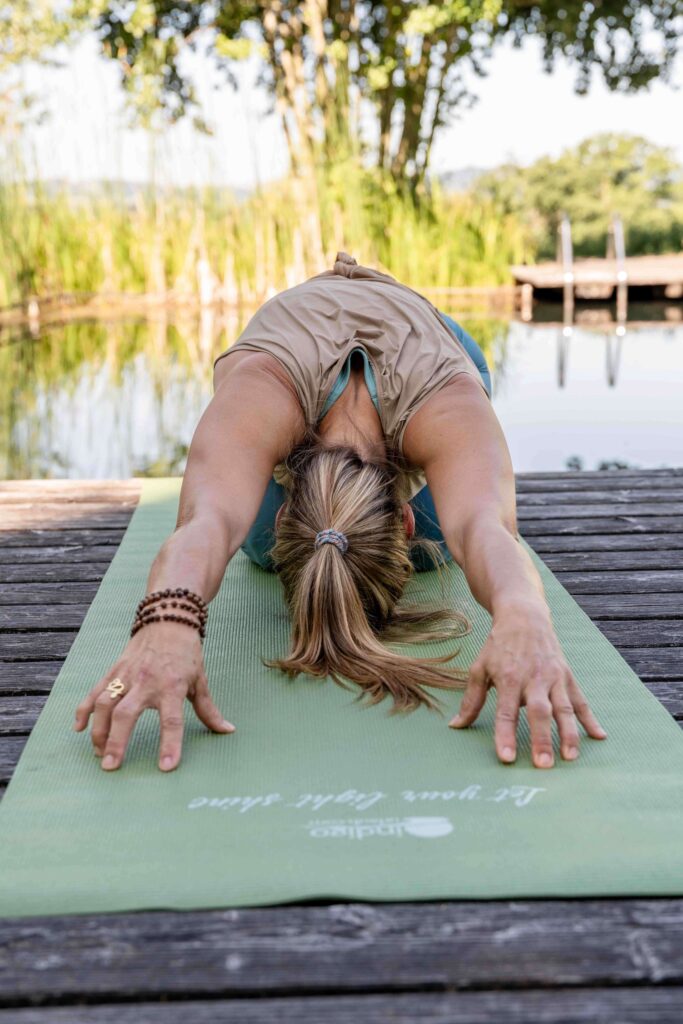 Frau macht Yoga am Teich.