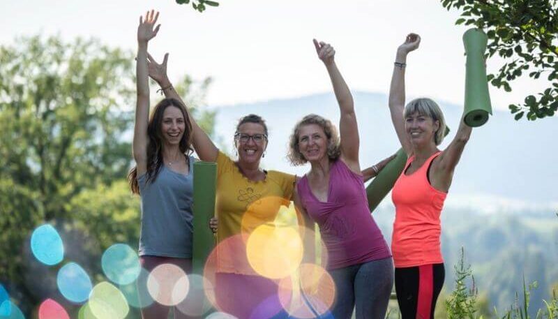 Gruppe von vier Frauen, die fröhlich sind und die Hände in die Höhe geben