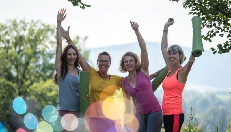 Gruppe von vier Frauen, die fröhlich sind und die Hände in die Höhe geben