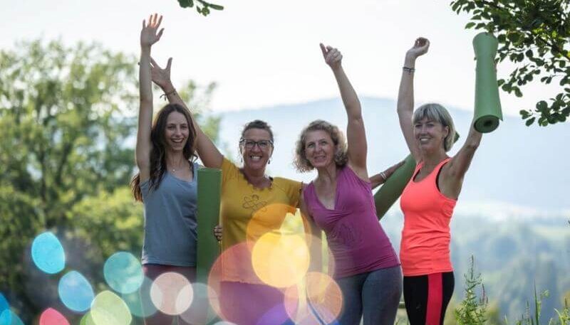 Gruppe von vier Frauen, die fröhlich sind und die Hände in die Höhe geben