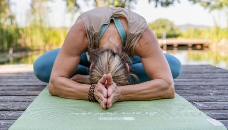 Frau, die Yoga auf einer Matte praktiziert