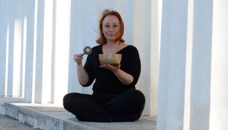 Frau meditiert mit Klangschale.