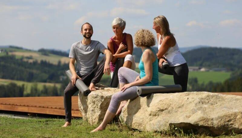 vier Menschen sitzen beisammen und reden, sportlich bekleidet
