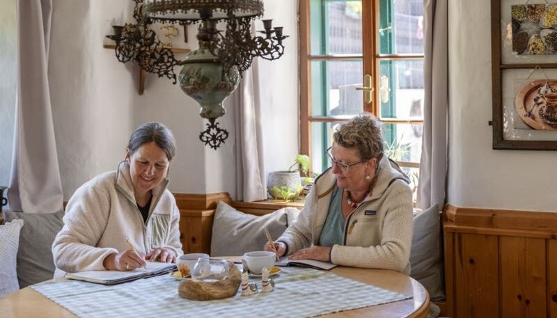 Zwei Frauen schreiben am Tisch.